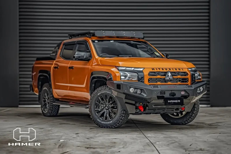 Orange Mitsubishi Triton fitted with a Hamer bull bar, roof rack and all-terrain tyres